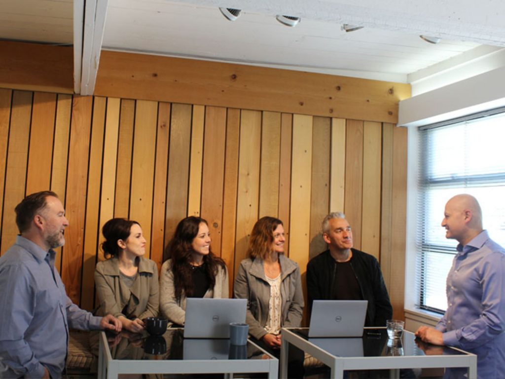 Team meeting in modern office with laptops, discussing business strategies and collaboration in a bright setting.
